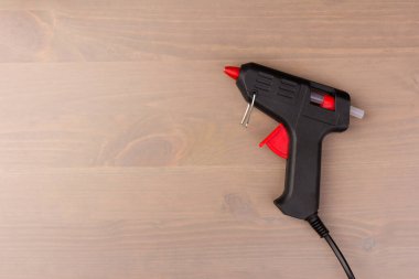 Sıcak eritilmiş silah, inşaat aletleri. Ahşap arka planda tutkal tabancası ve çubuklar.