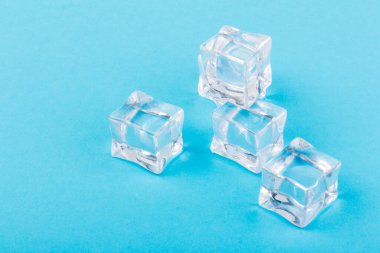 Şeffaf buz küpleri piramidi. Buz küpleri mavi arka planda kapanıyor. Metin için boşluk