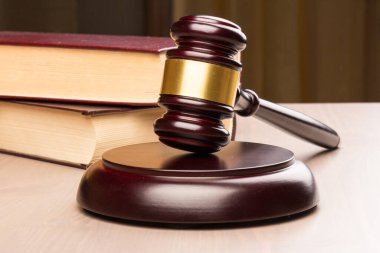 Kahverengi ahşap jüri tokmağı masaya yakın çekimde. Tahta masa, kitaplar. Mesaj için yer var. Hukuk ve Adalet teması