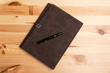 Tahta arka planda duran bir iş kalemi ve defter ile üst görünüm modelleme şablonu.