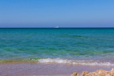 Yaz plajı ve deniz. Güneşli bir günde açık deniz manzaralı, gök mavisi bir sahil. Yaz tatili kavramı