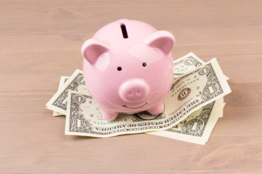 Ahşap arka planda dolar banknotları olan domuz kumbarası, mesaj için yer. Finans, tasarruf. İş başarıya ve emeklilik konsepti için biriktirmeye