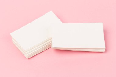 Pembe arkaplanda yakın planda beyaz kartvizit yığınları