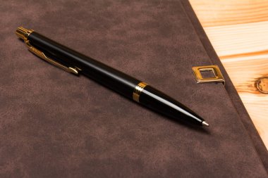 Tahta arka planda duran siyah bir kalem ve defter ile üst görünüm modelleme şablonu.