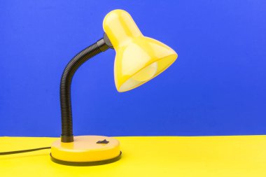 Sarı masa lambası mavi ve sarı arka planda izole edilmiş. Gündüz ve gece konsepti