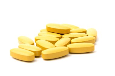 Sarı Multivitamin ve sünnet hapları, yakın plan beyaz zemin üzerine besin takviyesi