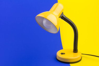 Sarı masa lambası sarı ve mavi arka planda izole edilmiş. Gündüz ve gece konsepti