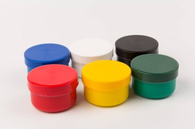 Beyaz arka planda çocukların yaratıcılığı için farklı renklerde boyalı kapalı plastik kavanozlar. Çizim için malzemeler, yaratıcılık, erken çocukluk gelişimi.