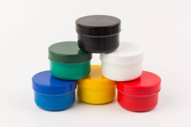 Beyaz arka planda çocukların yaratıcılığı için farklı renkte boyalar bulunan plastik kavanozlar. Çizim için malzemeler, yaratıcılık, erken çocukluk gelişimi.