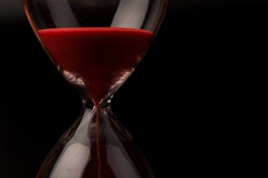 Kırmızı Kum, bir kum saatinin ampullerinin içinden geçerek bir geri sayım bitimine kadar geçen zamanı ölçüyor, fotokopi alanı olan siyah bir arkaplanda..