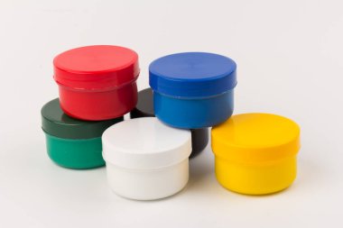 Beyaz arka planda çocukların yaratıcılığı için farklı renklerde boyalı kapalı plastik kavanozlar. Çizim için malzemeler, yaratıcılık, erken çocukluk gelişimi.