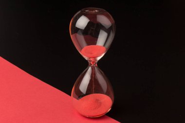 Kırmızı Kum, bir kum saatinin ampullerinin içinden geçerek, sürenin bitiş tarihine doğru, fotokopi uzayıyla birlikte siyah ve kırmızı bir arkaplanda geçişini ölçüyor..