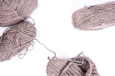 Örgü iğneleri ve beyaz arka planda koyu gri yün iplikler. Doğal yün örgü arka planı