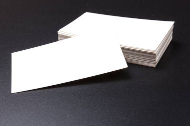 Siyah bir yüzeye yığılmış beyaz kartvizitler. Metin için boşluk