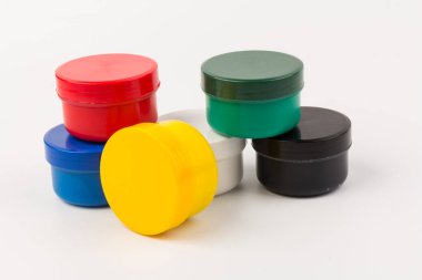 Beyaz arka planda çocukların yaratıcılığı için farklı renklerde boyalı kapalı plastik kavanozlar. Çizim için malzemeler, yaratıcılık, erken çocukluk gelişimi.