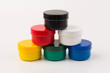 Beyaz arka planda çocukların yaratıcılığı için farklı renklerde boyalı kapalı plastik kavanozlar. Çizim için malzemeler, yaratıcılık, erken çocukluk gelişimi.