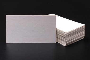 Siyah bir yüzeye yığılmış beyaz kartvizitler. Metin için boşluk