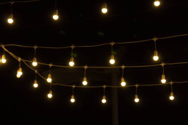 Siyah arka bahçenin önünde ateşten buğulanmış kıvılcımlar. Noel ve yeni yıl tatili konsepti. Odaklanmamış çelenk ışıkları, Bokeh etkisi. 