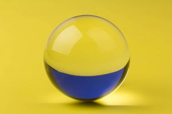 Glass ball on yellow background, glass globe ball