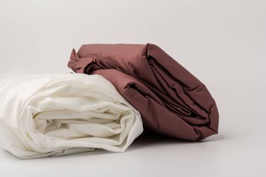 Katlanmış beyaz ve kestane rengi yatak çarşafları ve beyaz yastık kılıfları yığını; arkaplan; yakın plan.