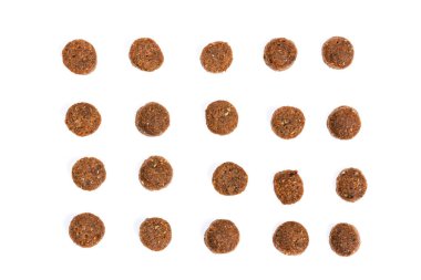 Kedi maması. Kuru kahverengi kedi maması yakın plan beyaz arka plana saçılmıştır.