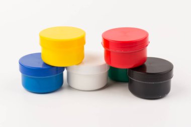 Beyaz arka planda çocukların yaratıcılığı için farklı renkte boyalar bulunan plastik kavanozlar. Çizim için malzemeler, yaratıcılık, erken çocukluk gelişimi.