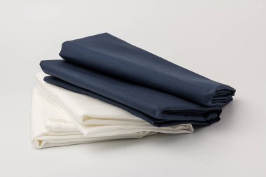 Beyaz üzerine katlanmış beyaz ve mavi yatak çarşafları ve yastık kılıfları yığını; arkaplan; kapanış.