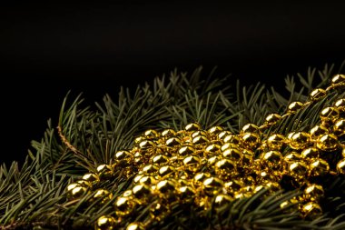 Ladin dalı ve altın boncuklar siyah bir otlağa saçılmış bir ipin üzerinde. Metin veya yazı için boşluk olan üst görünüm.