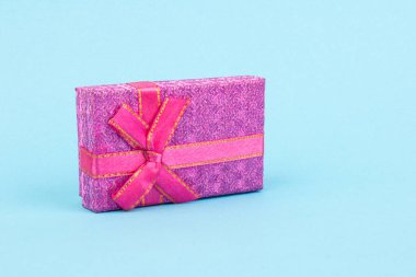 Mavi arka planda yay ve kurdeleli hediye kutusu. Hediye, sürpriz, ödül ikonu. Noel, doğum günü, tatil konsepti.