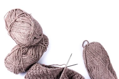 Örgü iğneleri ve beyaz arka planda koyu gri yün iplikler. Doğal yün örgü arka planı