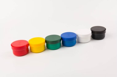 Beyaz arka planda çocukların yaratıcılığı için farklı renklerde boyalı kapalı plastik kavanozlar. Çizim için malzemeler, yaratıcılık, erken çocukluk gelişimi.