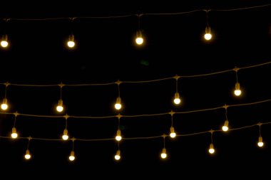 Siyah arka bahçenin önünde ateşten buğulanmış kıvılcımlar. Noel ve yeni yıl tatili konsepti. Odaklanmamış çelenk ışıkları, Bokeh etkisi. 