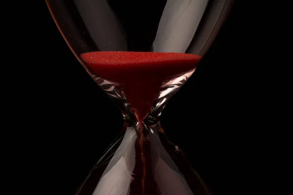 赤砂は 時間ガラスの球根を介して実行されているコピースペースと黒の背景に 締め切りにカウントダウンで通過時間を測定 — ストック写真