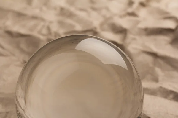 Glass ball on crumpled paper background, glass globe ball