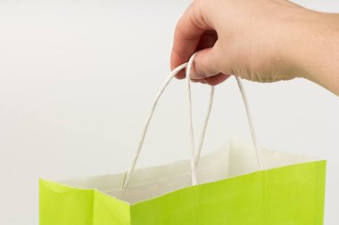 Hand holding Bright light green gift bag, isolated on white background