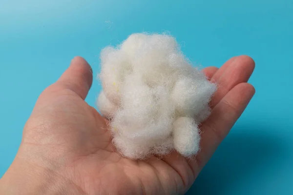 White Air Sintepon elinde. Yastık Malzemesi Tipi. Mavi arkaplan üzerinde Sintepon Doldurucu, yumuşak doku