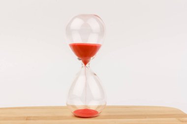 Kırmızı Kum, bir kum saatinin ampullerinin içinden geçiyor. Bir geri sayım bitimine kadar geçen zamanı ölçüyor. Tahta arka planda, fotokopi alanı ile birlikte..