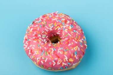 Çilek kremalı ve çok renkli donutlar, mavi arka planda izole edilmiş. Geleneksel tatlı hamur işleri. Metin için yer.