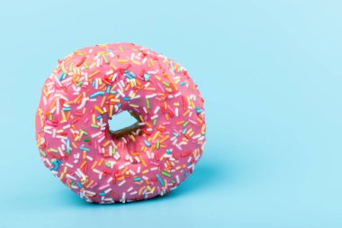 Çilek kremalı ve çok renkli donutlar, mavi arka planda izole edilmiş. Geleneksel tatlı hamur işleri. Metin için yer.