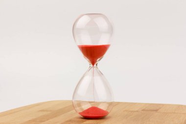 Kırmızı Kum, bir kum saatinin ampullerinin içinden geçiyor. Bir geri sayım bitimine kadar geçen zamanı ölçüyor. Tahta arka planda, fotokopi alanı ile birlikte..