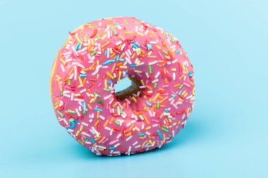 Çilek kremalı ve çok renkli donutlar, mavi arka planda izole edilmiş. Geleneksel tatlı hamur işleri. Metin için yer.