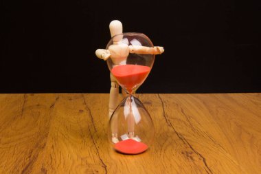 Kum saatinin yanındaki ahşap manken. Zamanı koru