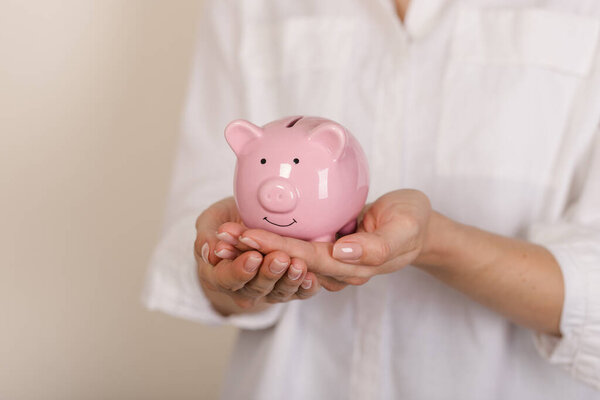 Piggy bank in hands on light background, space for text. Finance, saving money