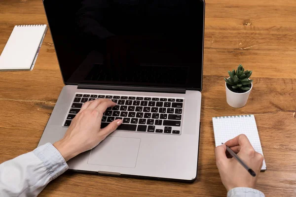 woman working with laptop on old wood table in modern coffee shop or loft. Mix of office supplies and gadgets on a wooden desk background. copy space.