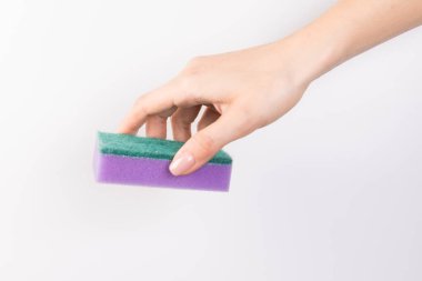 Kadının eli, beyaz arka planda izole edilmiş bir temizlik süngeri tutuyor.