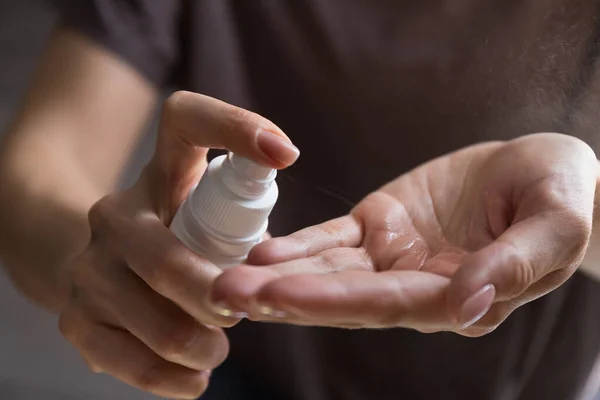 Woman applying spray disinfection alcohol product on hand. Disinfecting hands against virus bacteria, health prevention in day at home or work.