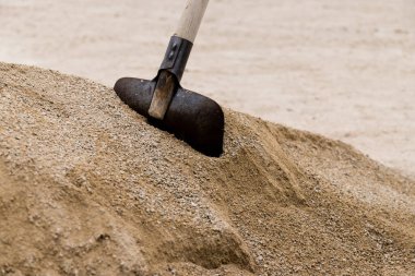 Kuma yakın çekim, küreği beyazlatır. Kum yığınlarından inşaat alanında çimento karışımına