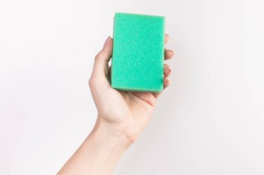 Kadının eli, beyaz arka planda izole edilmiş bir temizlik süngeri tutuyor.