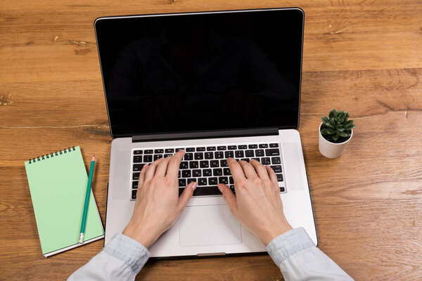 Woman working with laptop on old wood table. Mix of office supplies and gadgets on a wooden desk background. copy space.