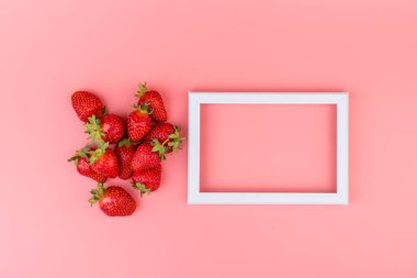 Pembe arka planda çilekler. Mesaj için boş çerçeve, çilek deseni. Yaratıcı gıda konsepti. Düz konum, üst görünüm, kopyalama alanı